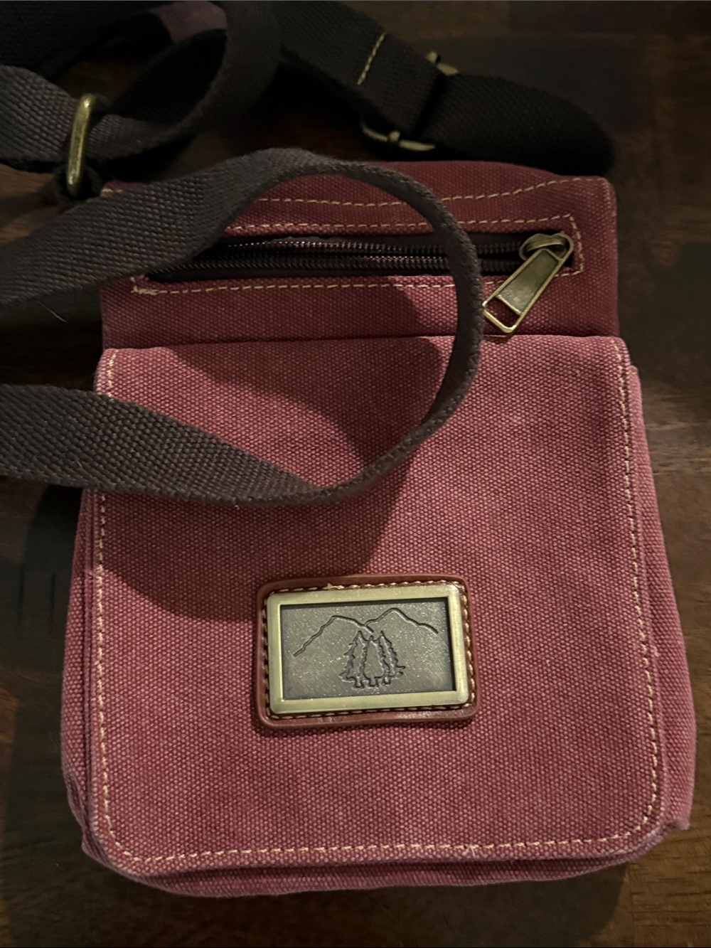 This is a Prairie Schooner canvas crossbody messenger bag in a reddish-maroon